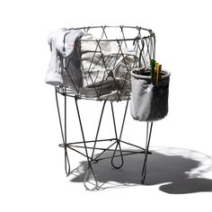 an iron wire basket with clothes hanging on it's sides and a pencil holder in the middle