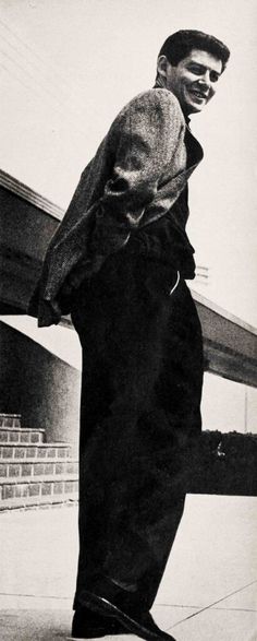 black and white photograph of a man leaning on a rail with his foot in the air