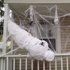 a house decorated for halloween with spider webs and plastic balls on the front porch