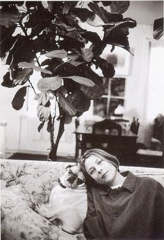 a woman laying on top of a couch next to a plant