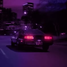 a car driving down the road at night with city lights in the backround