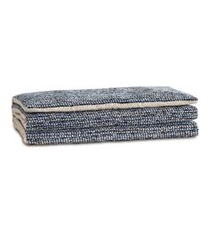 the blue and white tweed blanket is folded on top of each other