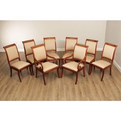 a set of eight chairs with beige upholstered back and seat cushions, in an empty room