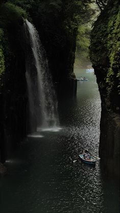 there is a boat in the water near a waterfall