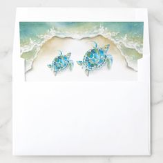 two sea turtles swimming in the ocean on a white envelope with blue watercolors