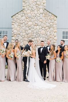 a group of people standing next to each other in front of a stone wall and building