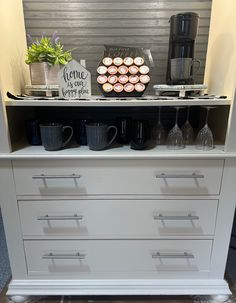 the coffee bar is organized with cups and mugs on it's dresser top