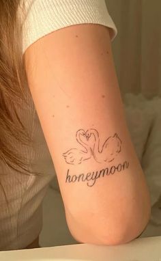 a woman with a tattoo on her leg that says honeymoon and two swans in the background