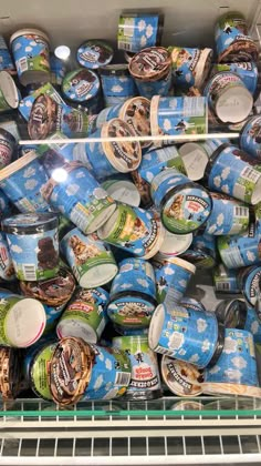 an open refrigerator filled with lots of frozen food and icecream cups on shelves