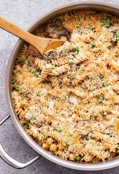 a large pot filled with pasta and meat covered in parmesan cheese, broccoli and peas