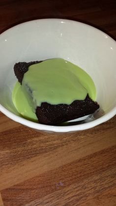 a white bowl filled with green cake on top of a wooden table