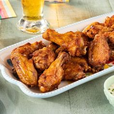 chicken wings on a plate next to a glass of beer