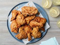 fried chicken on a blue plate next to glasses of wine and lemonades,