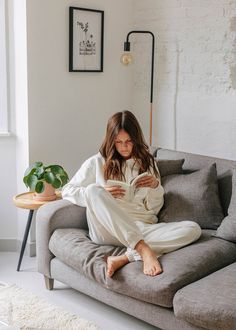 a woman sitting on a couch reading a book