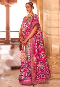 a woman in a pink and red sari standing next to some men sitting down