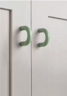 two green handles on white cupboards in a kitchen or dining room, one for the door and one for the drawer