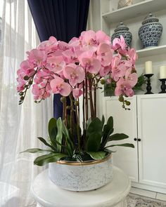 pink flowers are in a white vase on a table