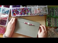 a person is making beaded bracelets with beads and plastic containers on the table