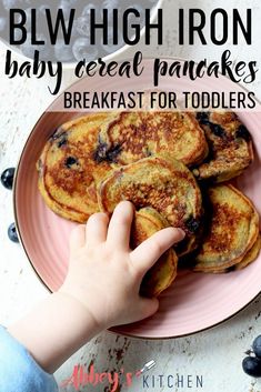 a child reaching for pancakes on a pink plate with text reading blw high iron baby cereal pancakes breakfast for toddlers