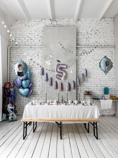 a birthday party with balloons and streamers on the wall behind a table in front of a brick wall