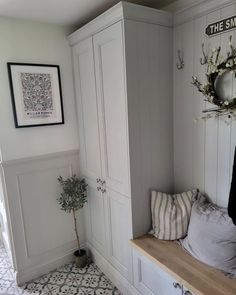 a room with white cabinets and a bench in the corner next to a potted plant