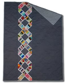 a quilted wall hanging on the side of a gray wall with different colored squares