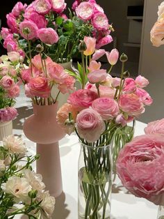 several vases filled with pink and white flowers on top of a table next to each other