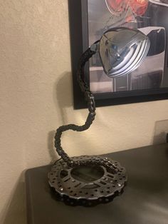 a metal object sitting on top of a black table next to a framed photograph and lamp