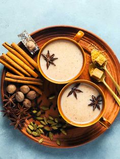 two mugs of coffee with cinnamon, star anise and spices on a plate