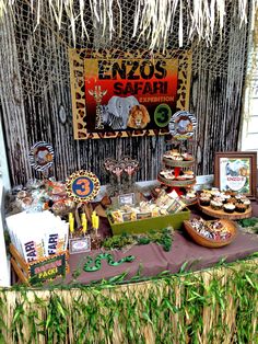 a table topped with lots of food and desserts next to a sign that says zoo safari