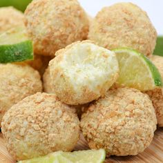 a pile of food sitting on top of a wooden cutting board next to limes