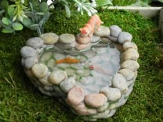 a fish pond with rocks in the shape of a heart and two goldfishs