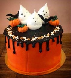 a halloween cake decorated with white ghost heads and black icing on an orange plate