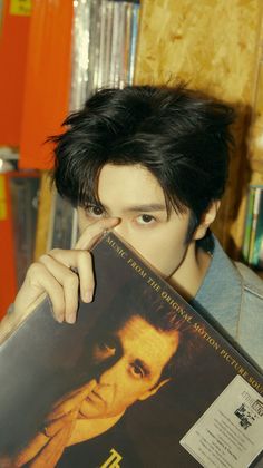 a young man holding up a book in front of his face