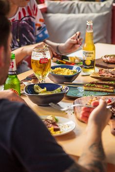 people sitting around a table eating food and drinking beer