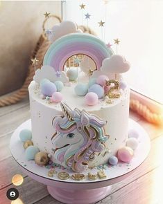 there is a white cake with a unicorn on it and rainbow decorations around the top