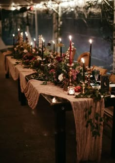 a long table with candles, flowers and greenery is set up for an event