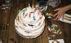 a white cake sitting on top of a wooden table covered in toy figurines