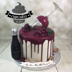 there is a cake with grapes on it and a wine bottle next to the cake