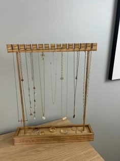 a wooden stand with many necklaces hanging from it's sides on a table