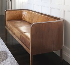 a brown leather couch sitting in front of a mirror on the side of a wall