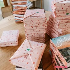 stacks of folded books sitting on top of a wooden table next to a stack of folded books