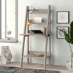 a wooden shelf with a laptop on top of it in front of a potted plant