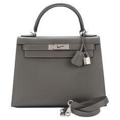 Hermes brand new Kelly 28 in Gris Mouette epsom leather with brushed palladium hardware and tonal stitching. It comes with a two strap with front toggle closure, clochette with lock and two keys, single rolled handle and removable shoulder strap. The interior has one zip pocket with Hermes engraved pull and two open pockets on the opposite side. Hermes Clothes, Kelly Hermes, Hermes Kelly 25, Hermes Kelly Bag, Grey Bag, Kelly Bag, Birkin 25, Full Look, Hermes Bags