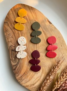 a wooden board topped with lots of different colored buttons next to some ears of wheat