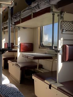 the inside of a train car with benches and tables on each side, looking out the window