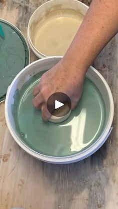 a person is mixing something in a bowl on a table with other bowls and pans