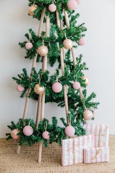 a christmas tree made out of wooden sticks with ornaments hanging from it's sides