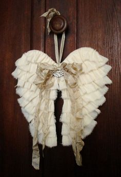 a white angel wings hanging from a wooden door with a button on the front and side