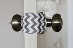 a close up of a door handle on a white door with grey and white chevron fabric